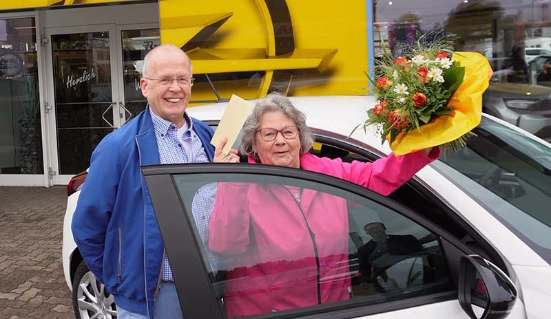 Ein Paar steht neben dem ersteigerten Opel Corsa.